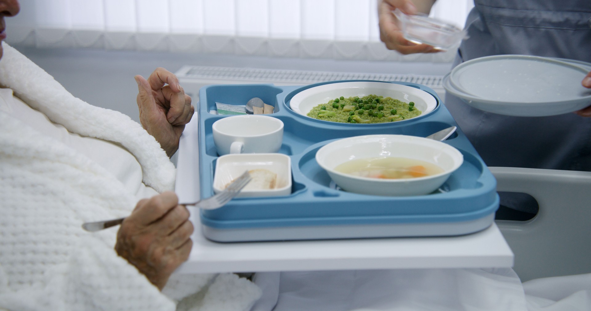 La enfermera abre una gran lonchera con comida a una paciente anciana